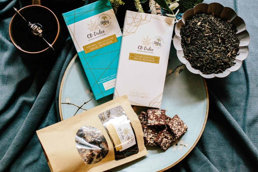 Flat lay of CBD Dulce dark chocolate bars and ingredients on a table setting.