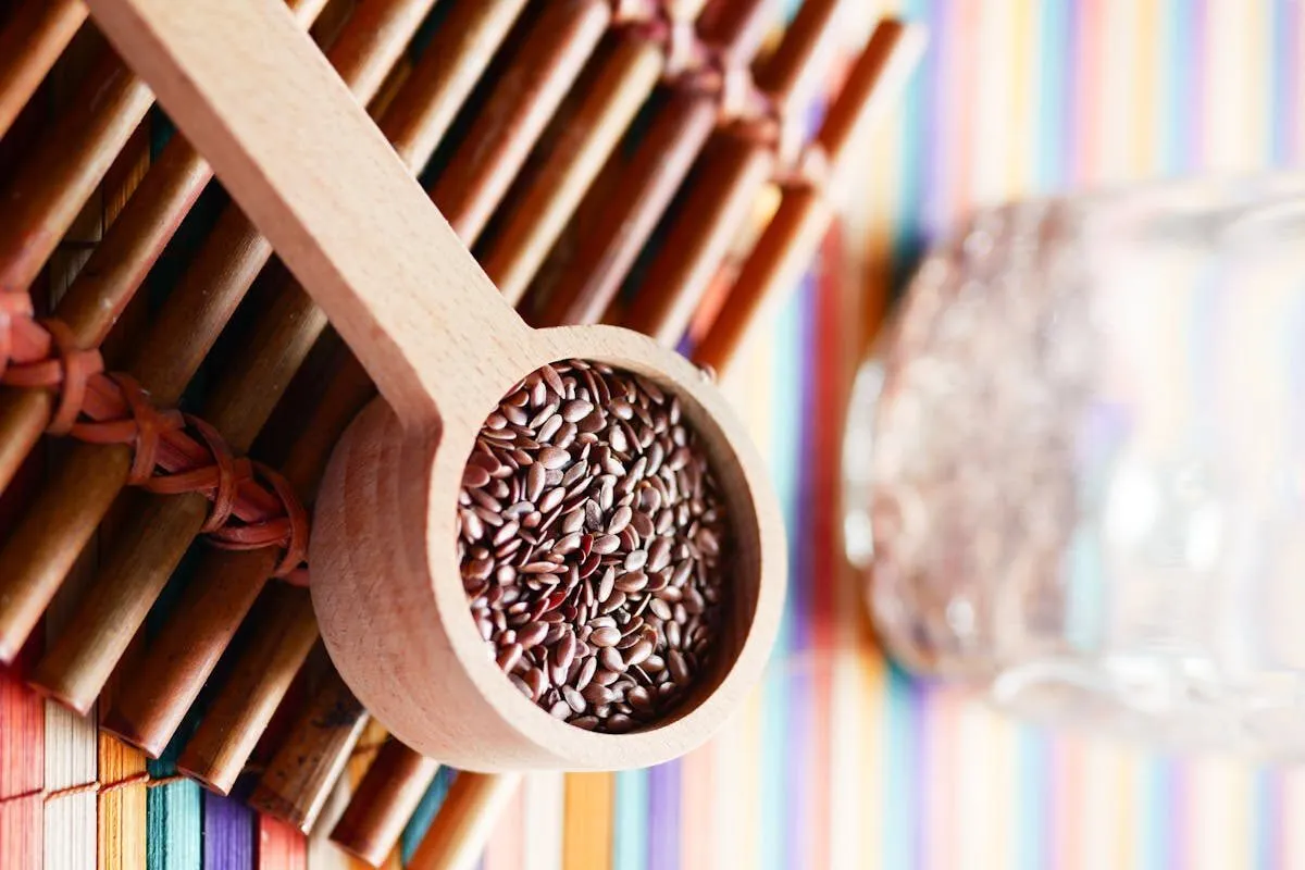 Vibrant close-up of flaxseeds in a wooden spoon on a colorful mat promoting healthy eating.