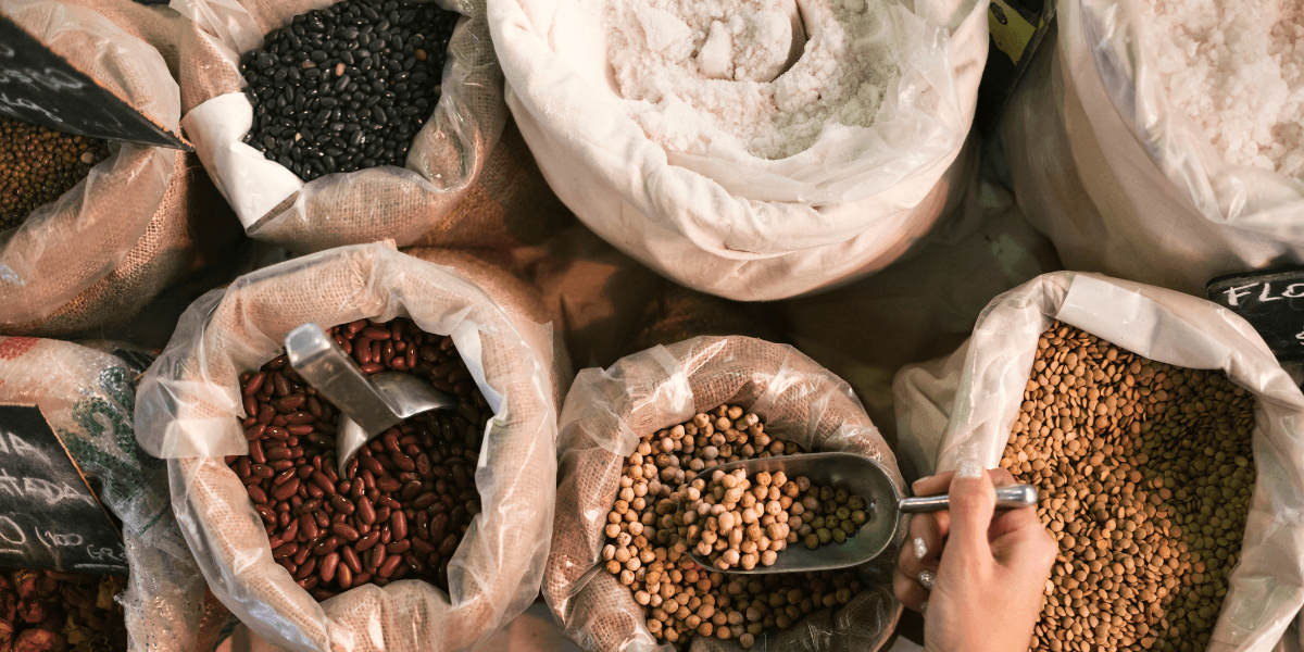 A person holds several bags filled with beans and various food items, showcasing a variety of groceries.
