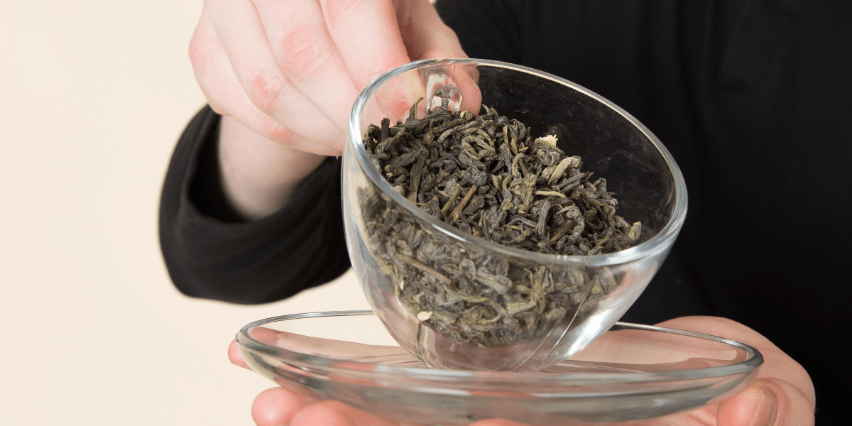 A person holding a bowl of green tea, showcasing the vibrant color and smooth surface of the beverage.