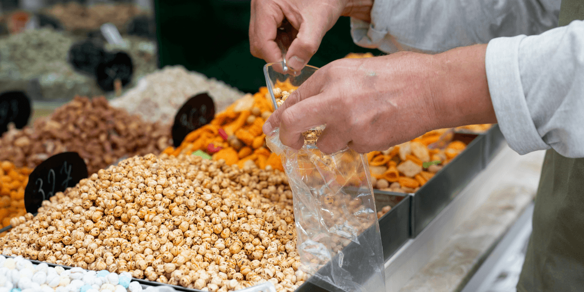 A man is selecting nuts from a display in a store.