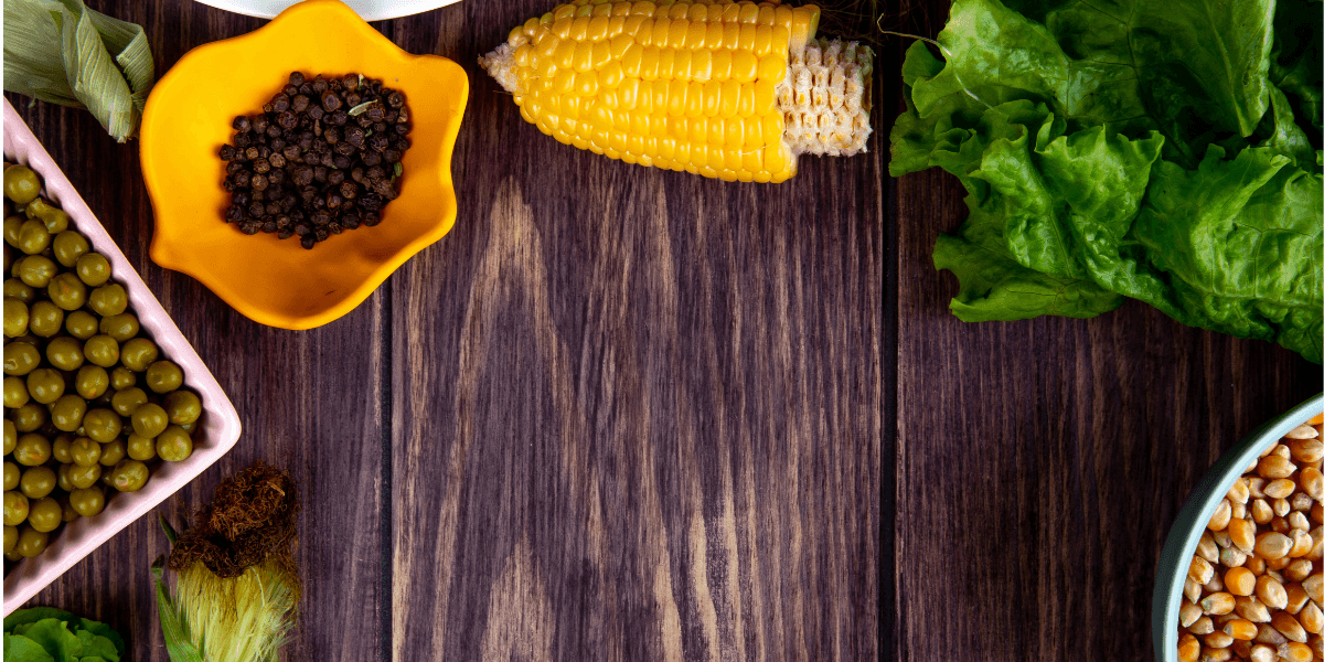  A bowl filled with beans, corn, and assorted vegetables placed on a rustic wooden table.